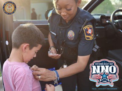 Police Officer putting sticker on young boy outdoors