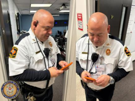Man wearing a security uniform looking at mobile phone while wearing radio earpiece