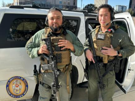 Two male police officers posing outdoors wearing special response team uniforms and holding police equipment