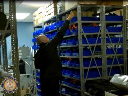 Man reaching for items on top shelf inside supply room