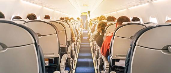 Forced perspective view looking up the isle of a plane with seats full of passengers