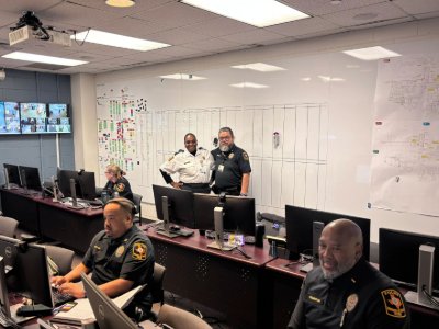 Police officers and uniformed security in room with computers