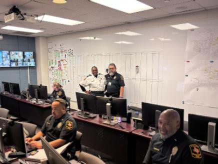 Police officers and uniformed security in room with computers