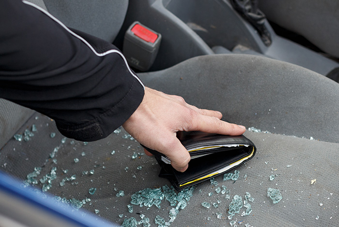 passenger side window smashed with glass on the seat and a man's arm reaching in grabbing a black wallet filled with money
