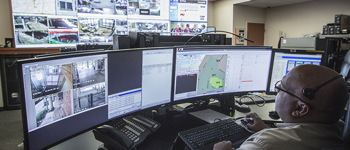A police telecommunications professional monitors activity on multiple screens.